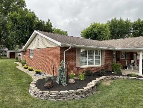 Cozy patio with cushioned chairs, small table, and surrounding greenery.