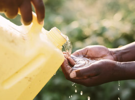 Image of child holding his hands over the water jug with pouring water