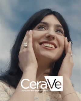 A woman touching her cheeks with a white CeraVe logo.