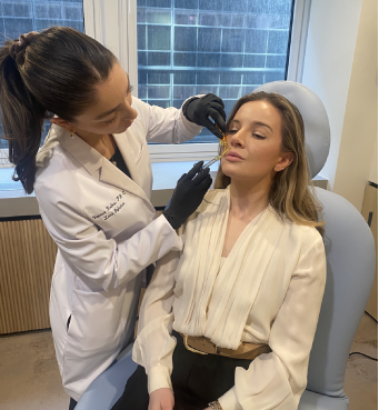 woman with brown hair and blue eyes sitting in orange chair and smiling 