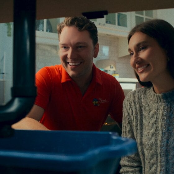 Image of plumber with client looking under sink area at the pipes
