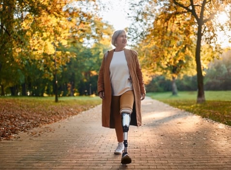 Woman with prosthetic leg walking in park