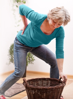 Woman with painful back trying to lift laundry basket