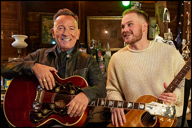 Musicians backstage holding guitars during an informal behind-the-scenes moment