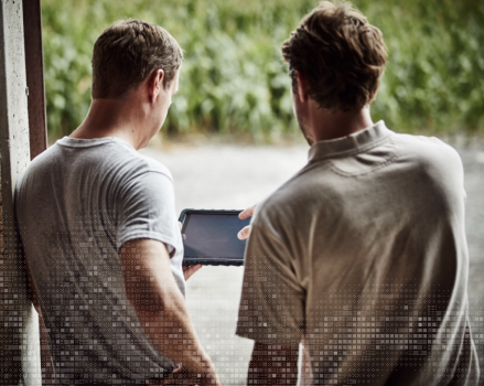 Two men standing and looking at an ipad