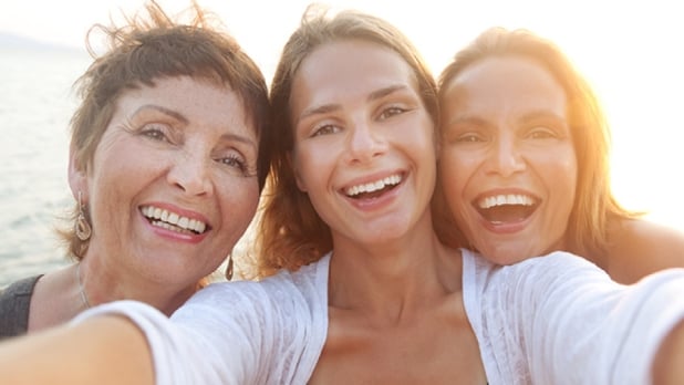 Three women smiling at the beach