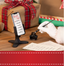 Santa with a quill pen marking down names on a list while using a WeatherTech DeskFone.