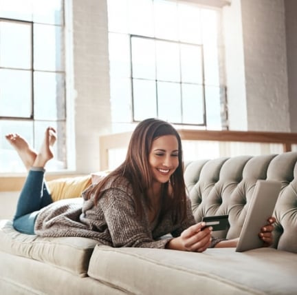 happy woman laying on the couch shopping