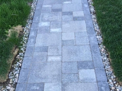 Gray stone pathway with grass and small pebbles bordering the edges.