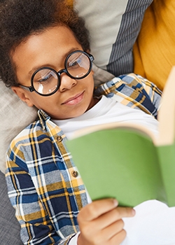 Young boy laying on his bed reading