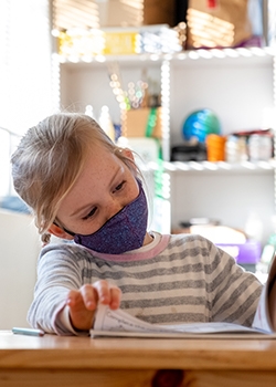 Your girl wearing a face mask and reading in school