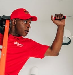 Handyman on ladder working on light