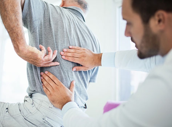 Person pointing to their back while doctor examines 
