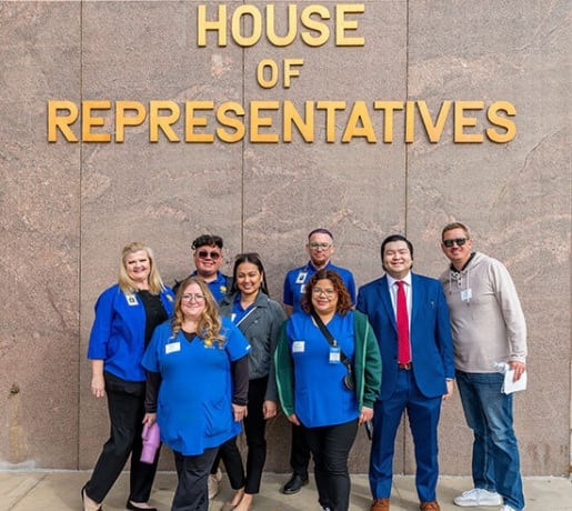 Group of people outside of building with "House of Representatives" on the wall