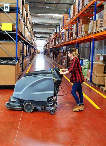 Woman cleaning warehouse floor