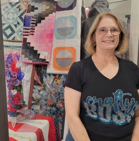 Woman standing in front of quilts