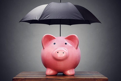 Photo of a piggy bank with an umbrella representing asset protection