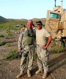Two military members next to military vehicle 