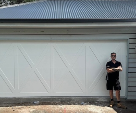 exterior of garage door with the owner standing in front