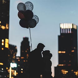 Couple with balloons in front of the skyline