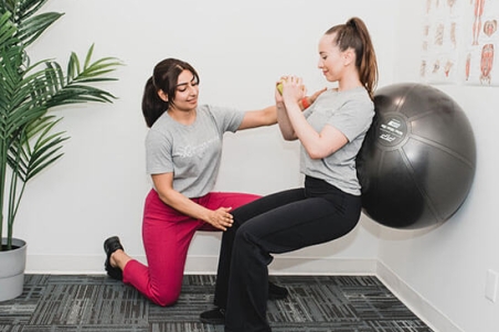 Professional working with patient with an exercise ball on the wall
