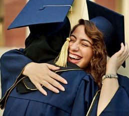 Two graduates smiling and hugging