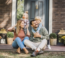 Family smiling while sitting outside home