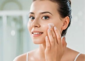 Woman applying lotion to her face