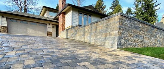 Front of home with retaining wall and paver driveway 