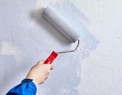 Person painting a wall with a paint roller