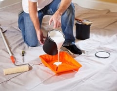 Person pouring paint into a paint tray