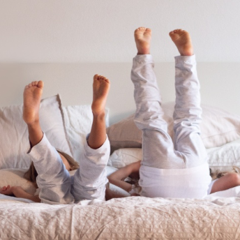 Zwei Kinder liegen auf dem Bett und strecken Füße in die Luft