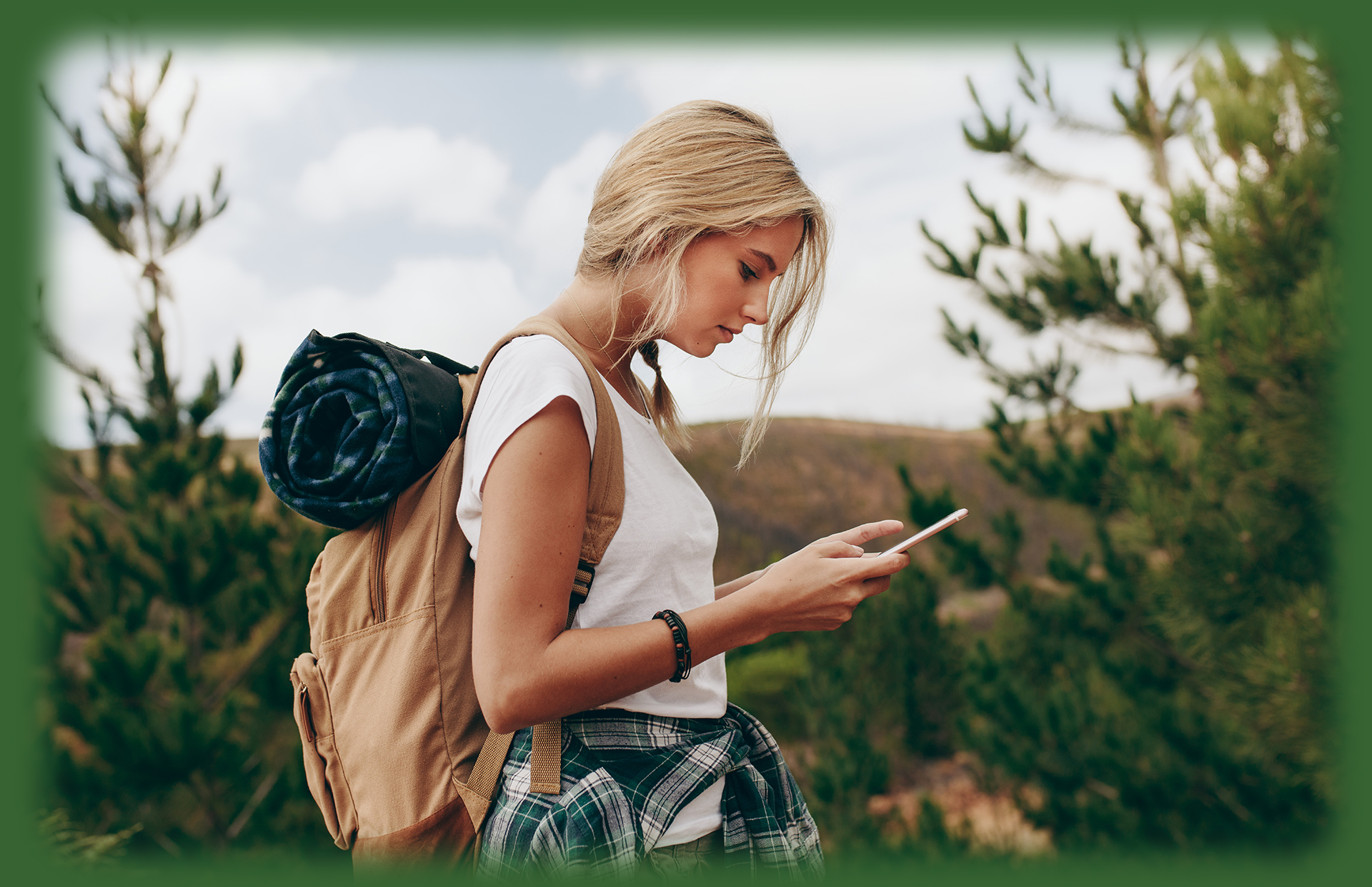 woman looking at cellphone while wearing a hiking pack