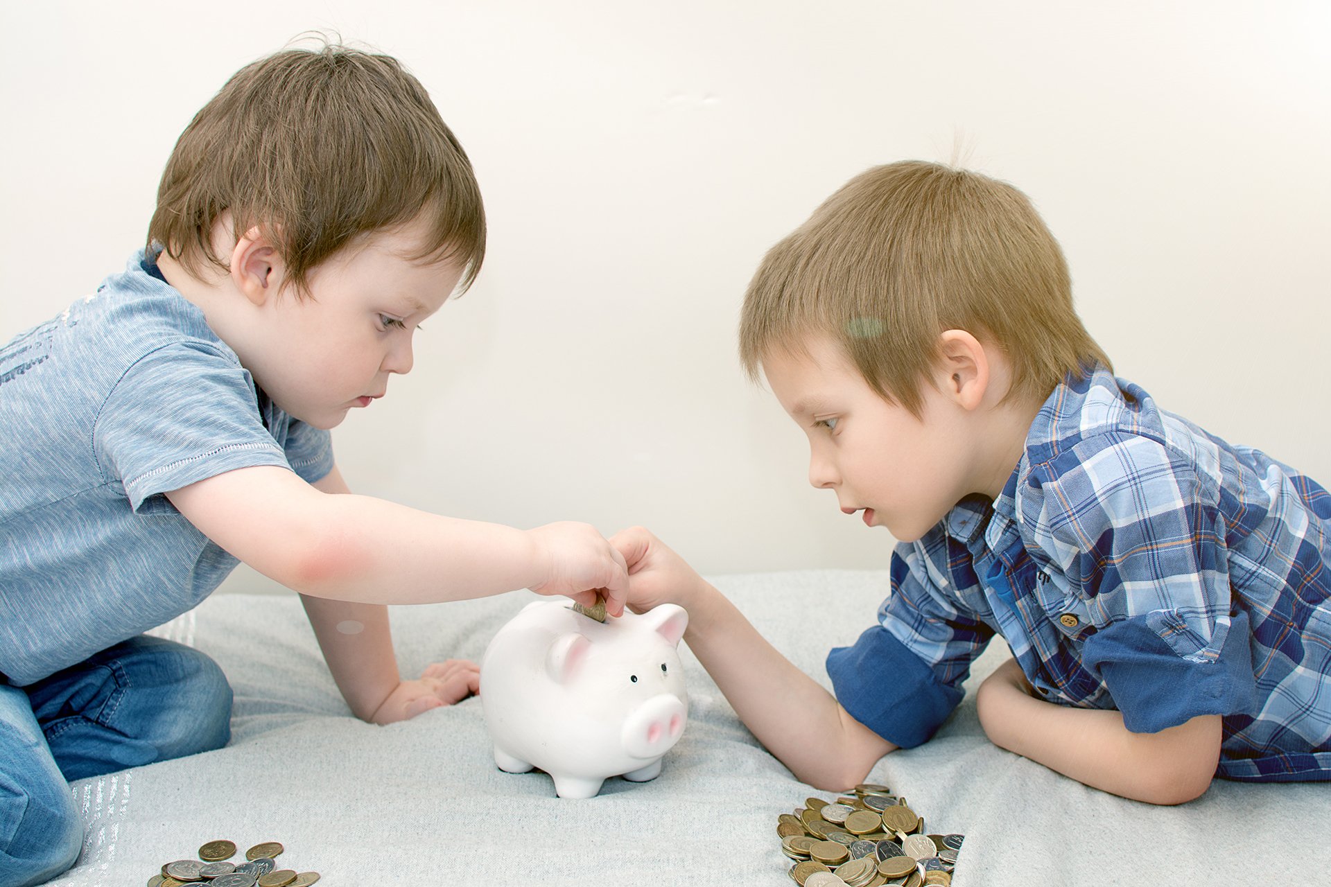 two kids putting coins in a piggy bank