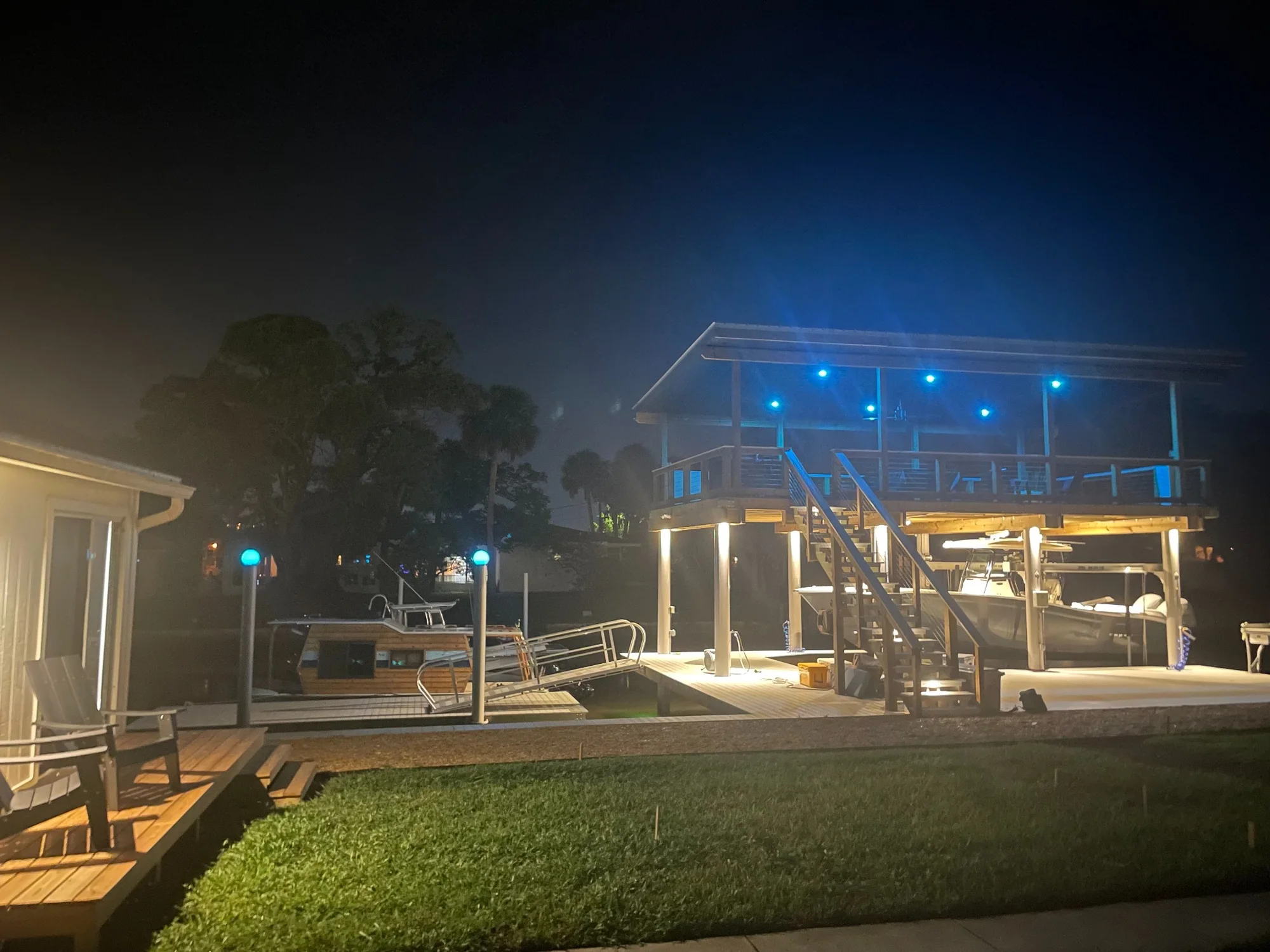 Final wide night view of a custom dock with blue upper-deck lights and warm lower-deck lights