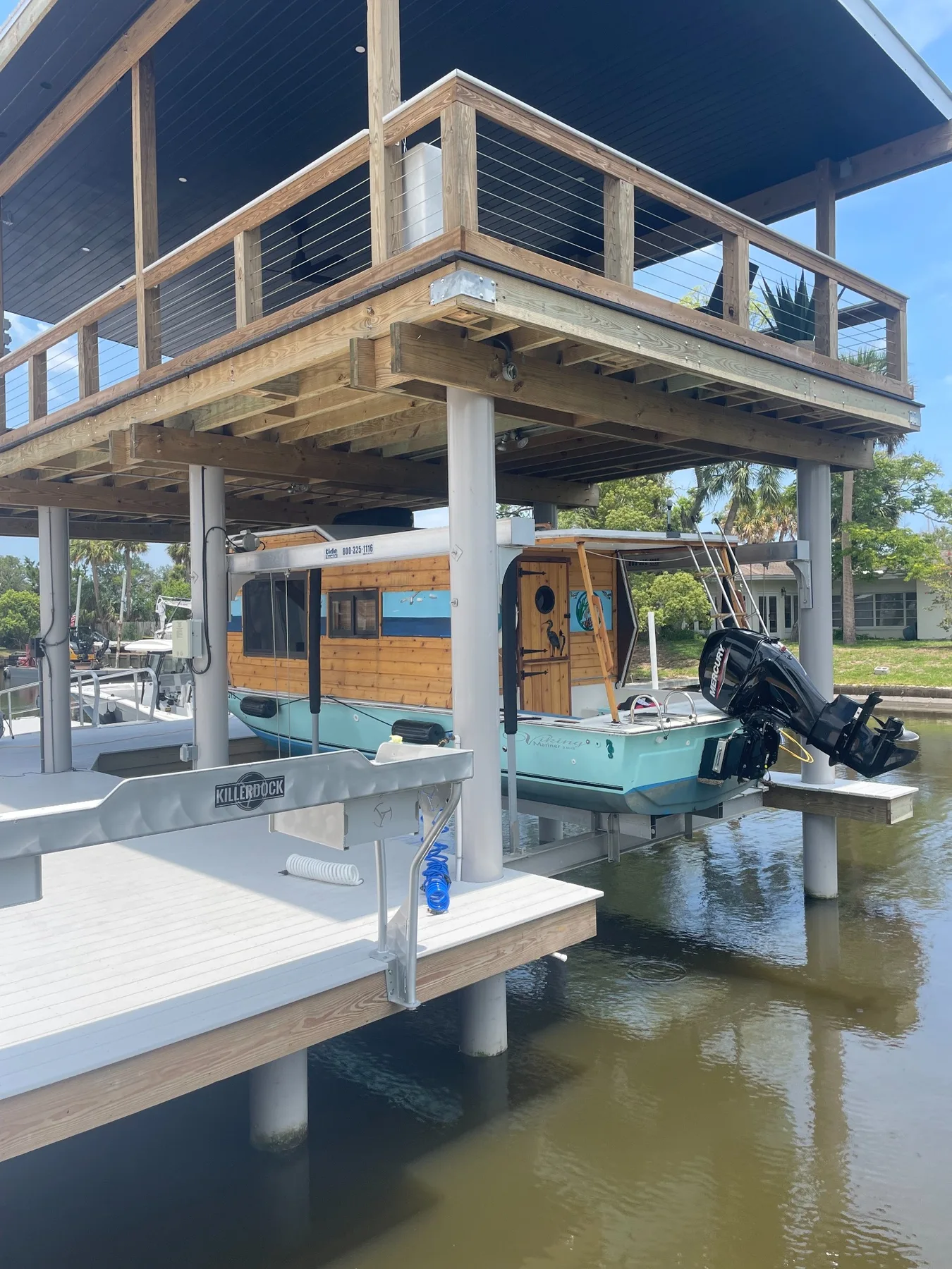 Boat raised on a custom lift beneath an elevated waterfront deck
