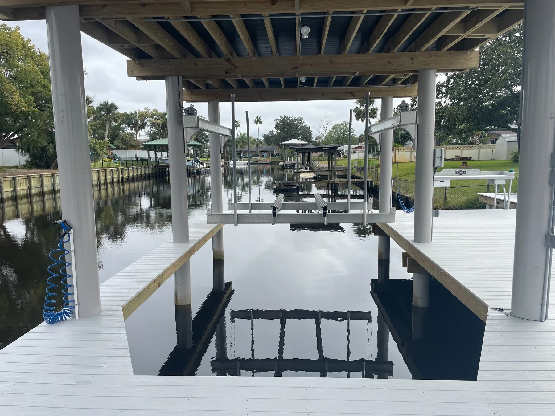 Daytime view beneath the dock showing a boat lift bay and walk-around decking