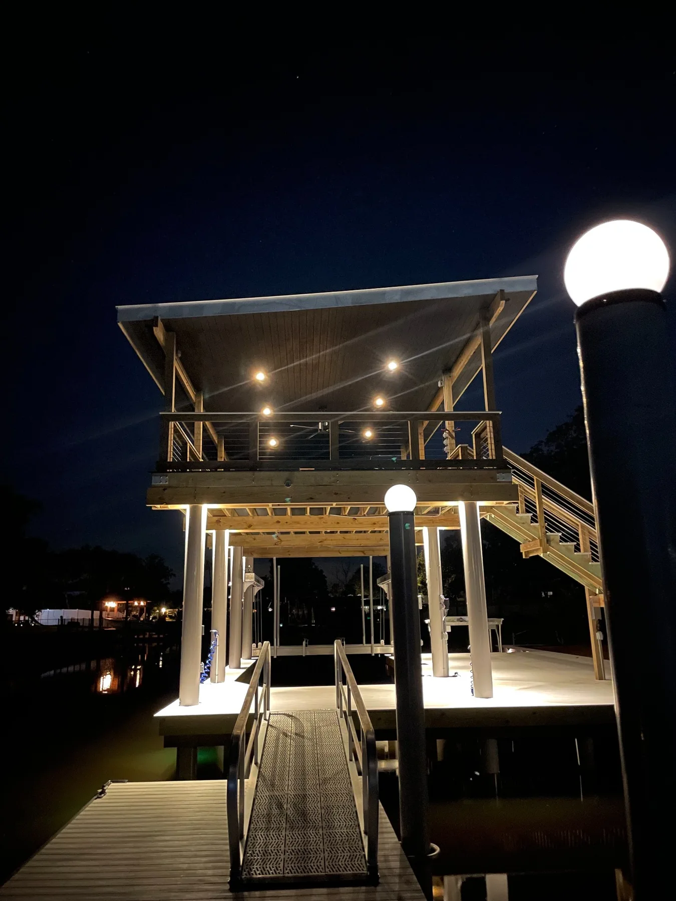 Front water approach to a completed two-level dock with gangway and warm lighting