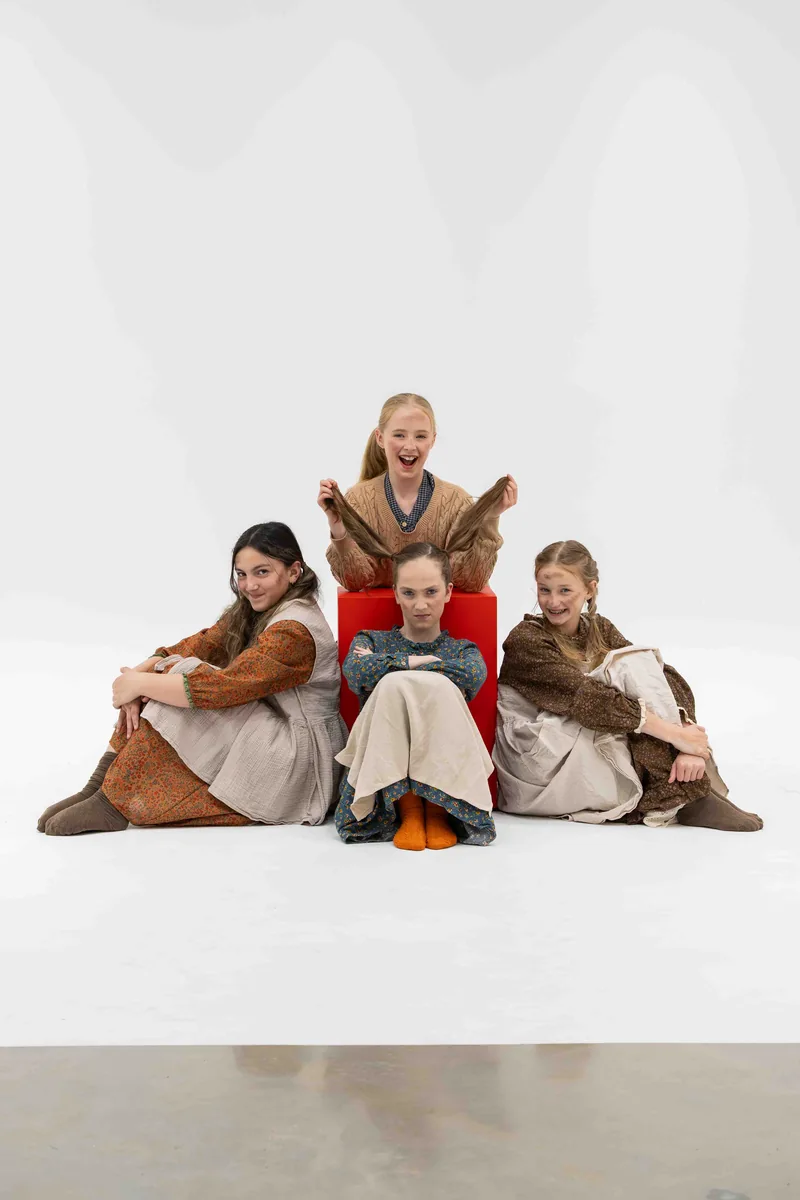 Four cast members dressed as the orphans, striking playful poses