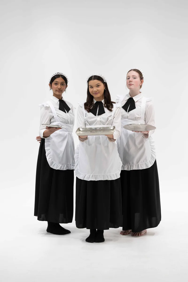 Three mansion staff members in black and white uniforms