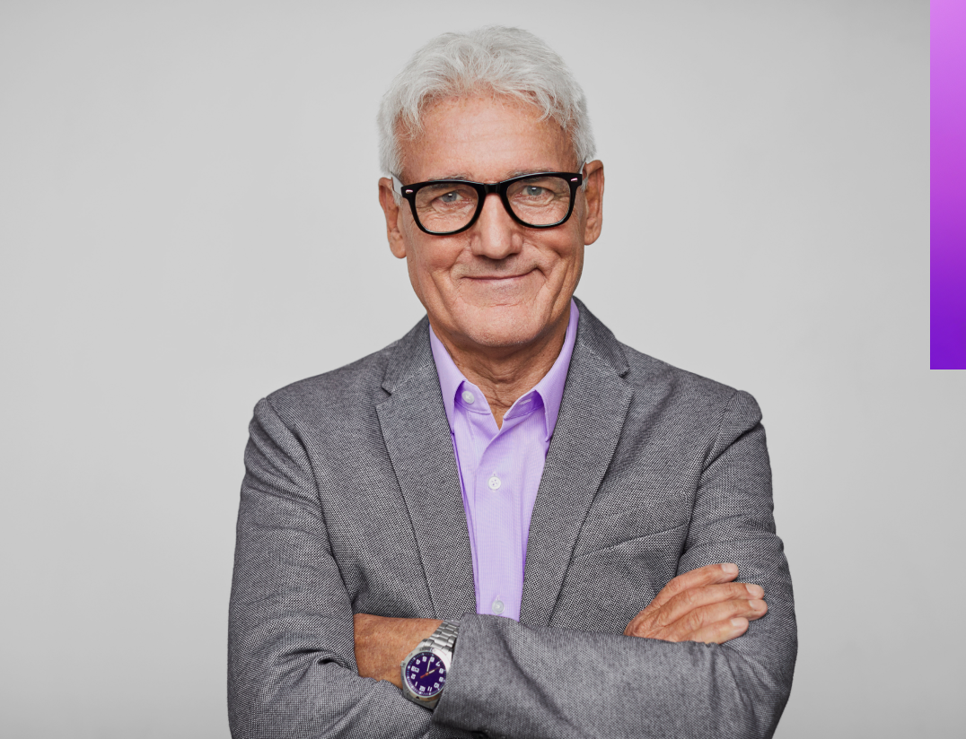 man wearing grey suit with arms crossed. purple decorative line