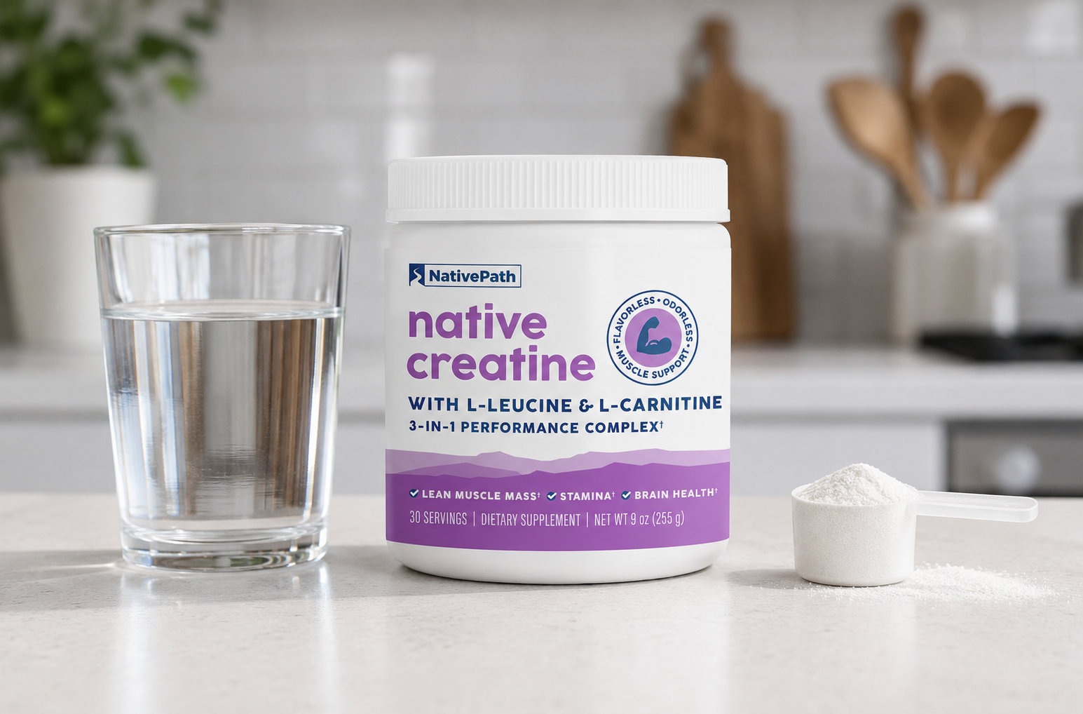 A jar of NativePath Native Creatine on a kitchen counter with a glass of water and the scoop