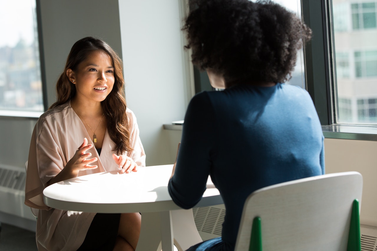 Two women learning English talking at a table