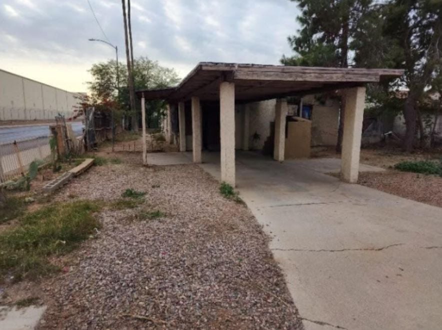 Older home with a detached carport and worn exterior, suitable for renovation or cash sale.