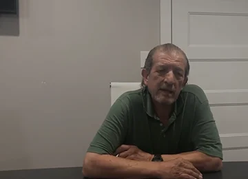 Homeowner seated at a table in a Joe Homebuyer office, giving a testimonial about their selling experience.