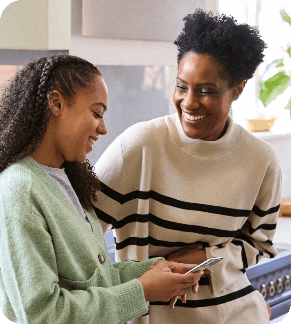 Mom and daughter smiling with daughter holding an Aura Protected Mobile device in hand