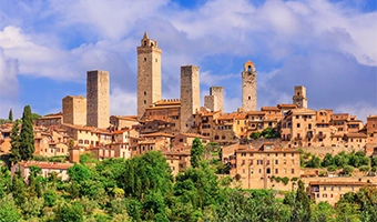 Historic hill town with stone towers and warm-toned buildings.