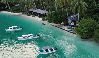 Tropical beach with boats anchored in turquoise water.