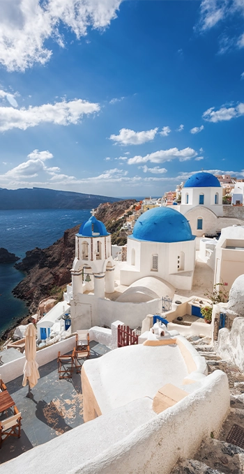 White cliffside village with blue domes overlooking the sea.
